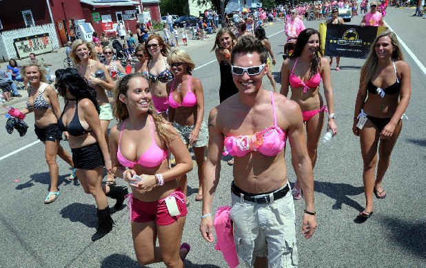 A woman and a man both wearing pink bikini tops while marching on parade